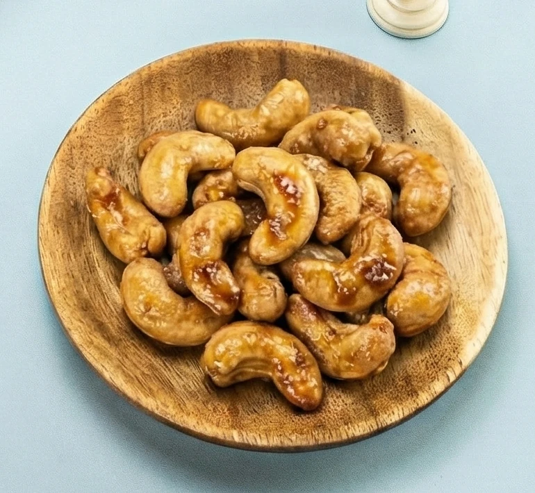 A close-up of Honey cashews in a wooden bowl.